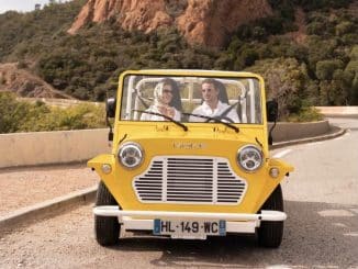 Moke électrique Mk2 jaune vue de face sur une route côtière, deux occupants