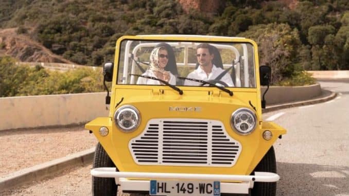 Moke électrique Mk2 jaune vue de face sur une route côtière, deux occupants